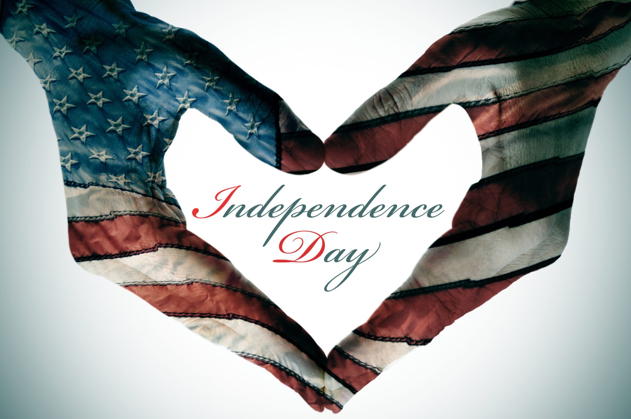 man hands patterned with the flag of the United States forming a heart and the sentence independence day