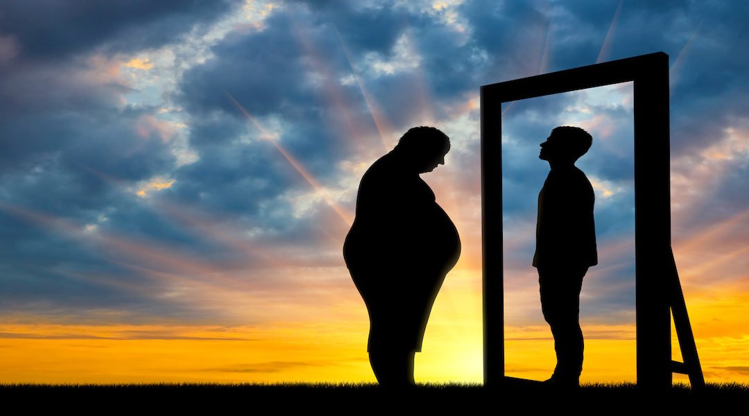 Fat sad man and his reflection in the mirror of a normal man against sky.